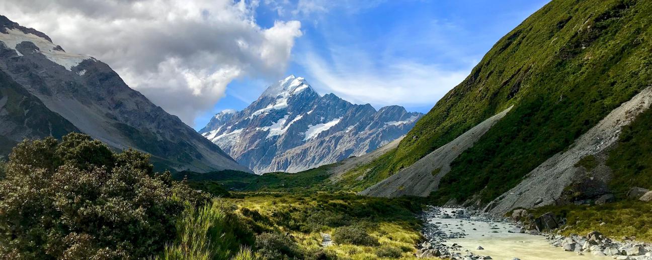 View of Aoraki / Mount Cook from a distant valley with clouds rolling over