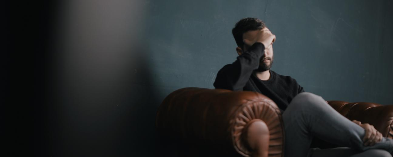 Man sitting on couch with hand over face