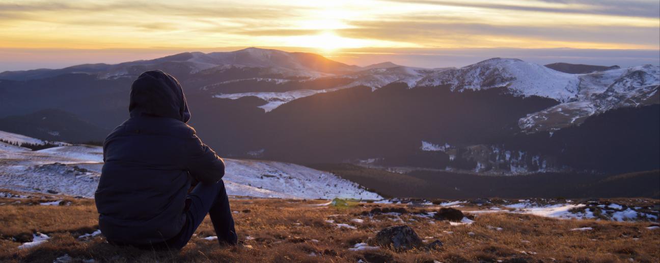 Person sitting looking at snow covered mountains