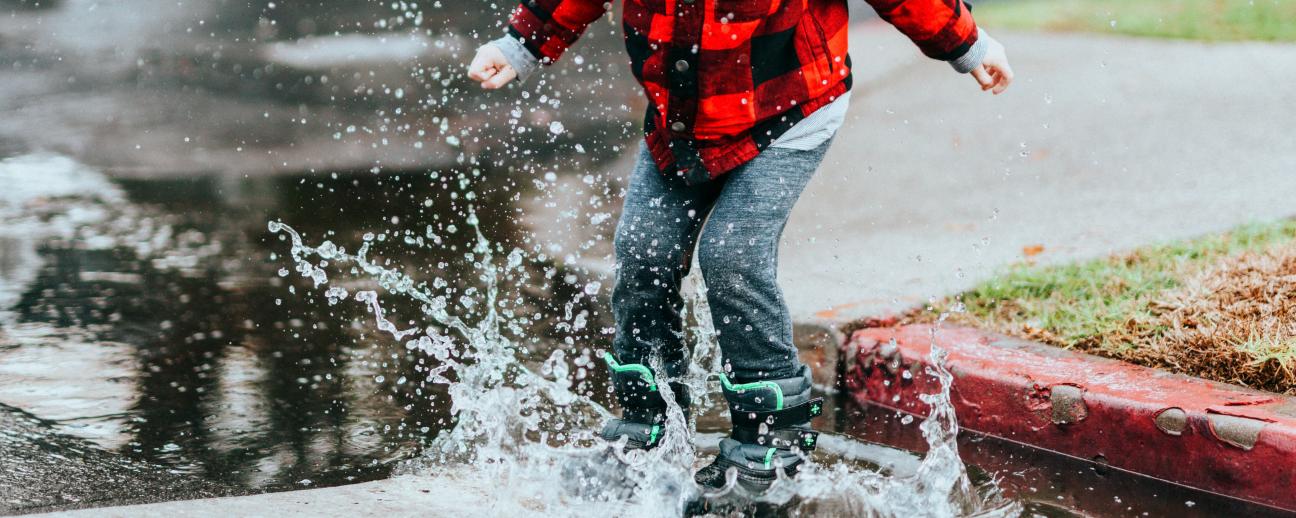 Young boy jumping in puddle