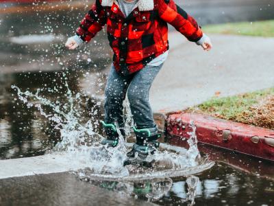Young boy jumping in puddle