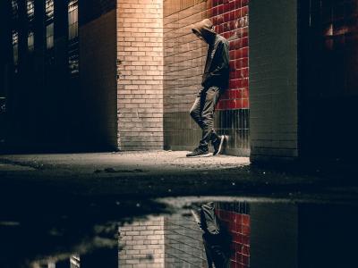 Man standing under street light with reflection in puddle